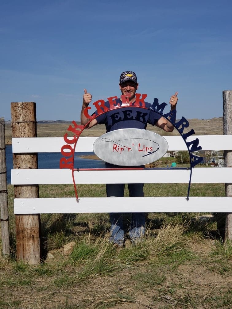 Rock Creek Marina owner with the marina sign at Fort Peck Lake